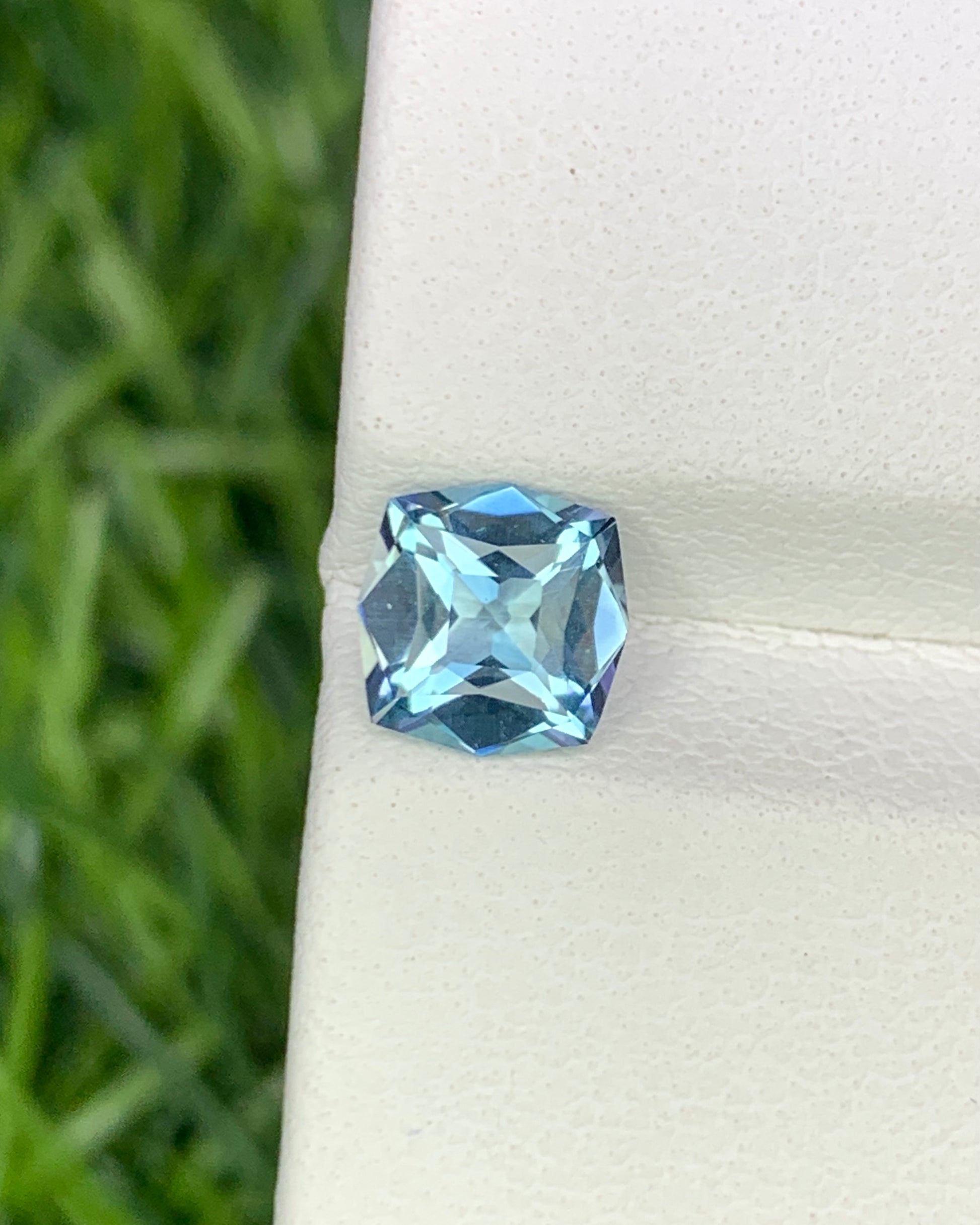 Blue gemstone on a white stand with a blurred green background