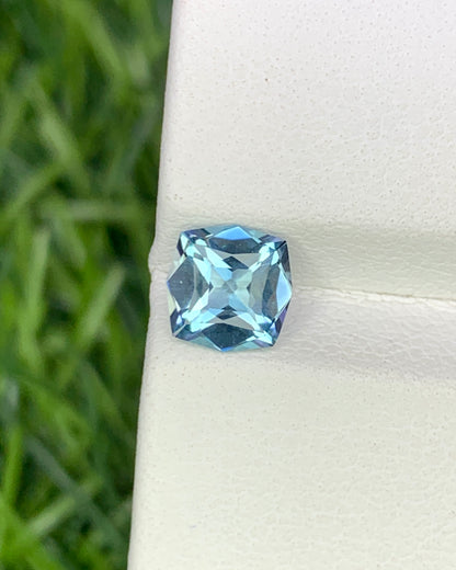 Blue gemstone on a white stand with a blurred green background